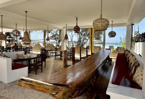 a large wooden bench in a room with tables and chairs at Kiwengwa Bungalow Boutique Resort in Kiwengwa