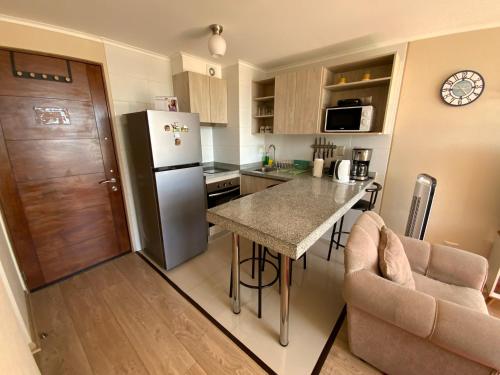 a small kitchen with a refrigerator and a table at Arriendo 1 Departamento Diario Amoblado en Edificio Pleno Centro de Osorno Full Eléctrico y Estacionamiento Techado, Comodidad, Moderno y Seguridad in Osorno