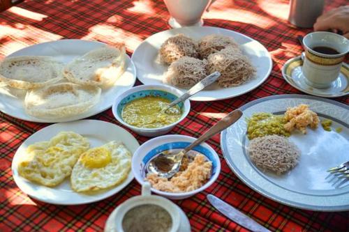 een tafel met borden ontbijt erop bij Lake Side Safari Bungalow in Udawalawe