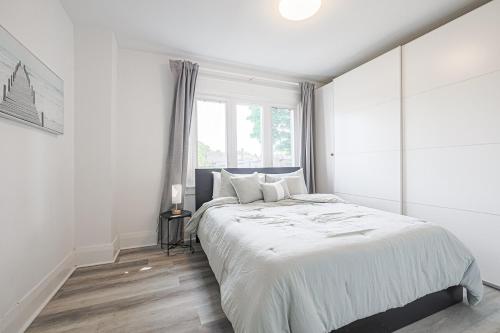 een witte slaapkamer met een groot bed en een raam bij Cozy & Comfy house near Subway in Toronto