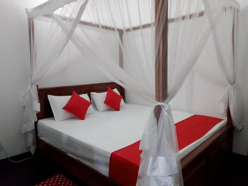 1 dormitorio con cama con dosel y almohadas rojas y blancas en Ocevia - Tangalle, en Tangalle