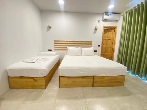 two beds in a room with green curtains at Thila Sky View in Thoddoo