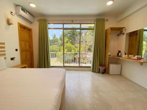 a bedroom with a bed and a large window at Thila Sky View in Thoddoo