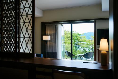 Zimmer mit einem großen Fenster, einem Tisch und Stühlen in der Unterkunft Hakone Hotel in Hakone