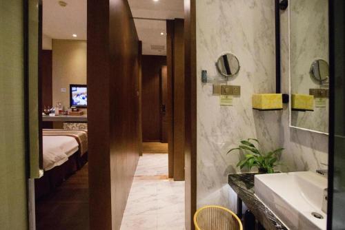 a bathroom with a sink and a bedroom with a bed at Southeast Peninsula Hotel Quanzhou in Quanzhou