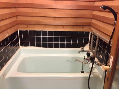 a bath tub in a bathroom with black tiles at Kakeyu Onsen Hotel Kameya in Ueda