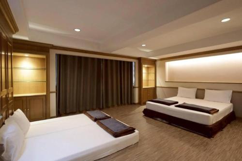 a bedroom with two beds and a large window at Alameda Suites Hotel in Bangkok