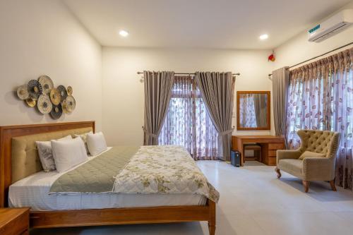 a bedroom with a bed and a chair and windows at Sandila Villa in Matara
