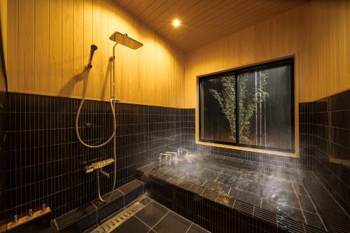 a bathroom with a tub with a shower and a window at Takenoyado Beppu in Beppu