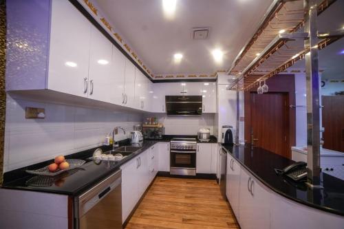 Una cocina con gabinetes blancos y una encimera negra. en Victorian Venue Hotel, en Katmandú