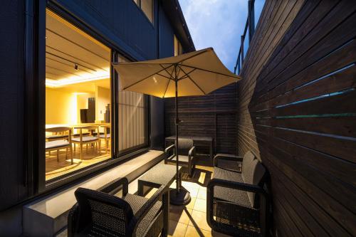 a patio with chairs and an umbrella on a balcony at Takenoyado Beppu in Beppu