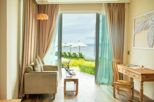 a living room with a desk and a window with a view at Vannee Golden Sands Beachfront Resort in Haad Rin