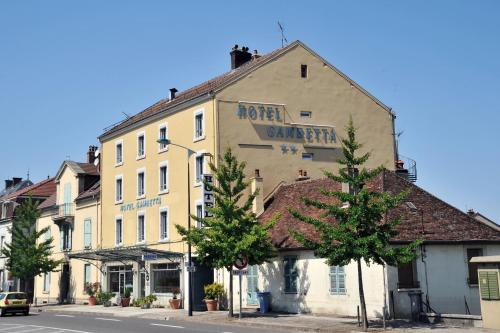 un edificio en una calle con árboles delante en Hôtel Gambetta en Lons-le-Saunier