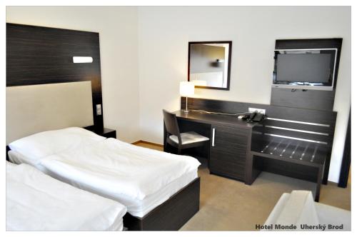 a bedroom with a bed and a desk and a mirror at Hotel Monde in Uherský Brod