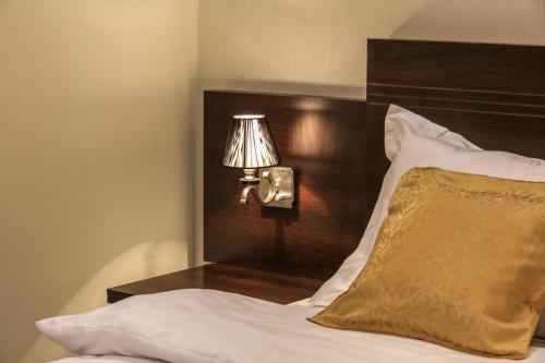 a bed with a wooden headboard with a lamp and a pillow at Al Itqan For Serviced Apartments-الاتقان للشقق المخدومة in Jeddah