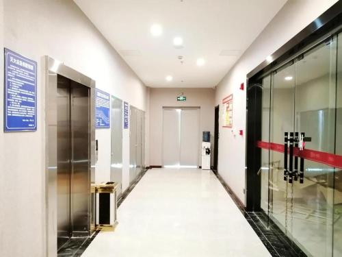 un couloir vide dans un immeuble avec ascenseur dans l'établissement Pai Hotel Guang'an Railway North Station, à Guang'an