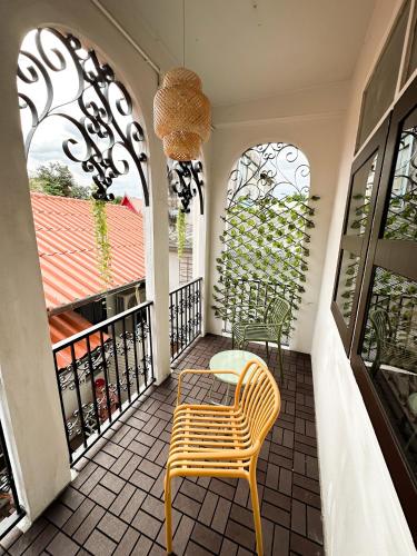 a balcony with a yellow chair and two windows at Bangkok Neighborhouse in Bangkok