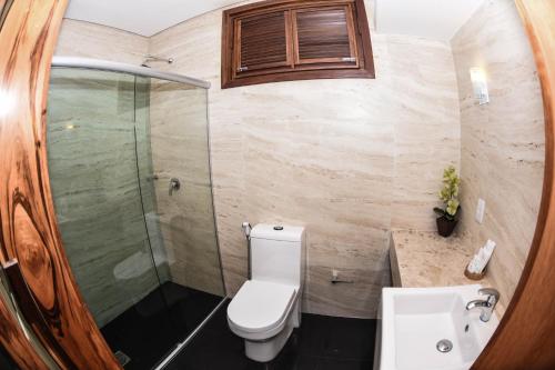 a bathroom with a toilet and a glass shower at Genus Beach Hotel in Lagoinha