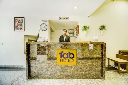 a man standing behind a counter with a job holders sign at FabHotel Solitaire Inn in Kānpur