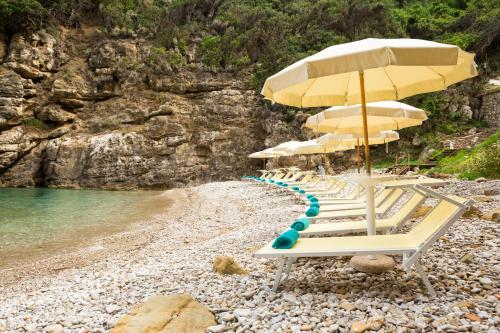 a group of lounge chairs with umbrellas on a beach at Relais Regina Giovanna in Sorrento