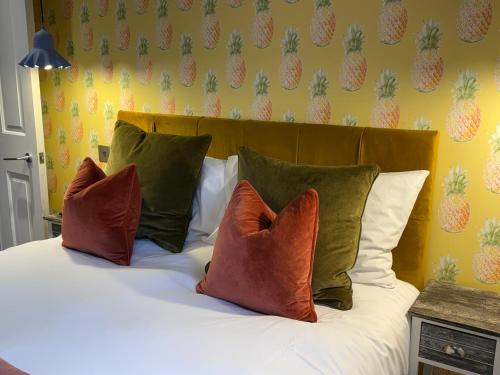 a bed with four pillows on it with pineapple wallpaper at Dream Stays Bath - Kingsmead Street in Bath