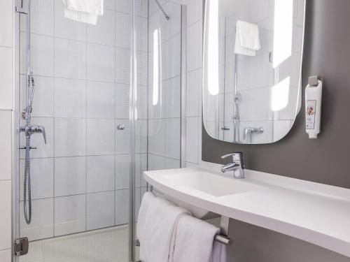 une salle de bain avec un lavabo et une douche dans l'établissement ibis Zürich Messe Airport, à Zurich