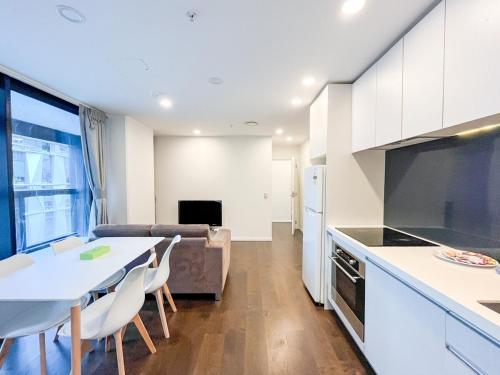 une cuisine et un salon avec une table et un canapé dans l'établissement Chic 2BR City Central Apt w Pool & Sauna & Gym, à Auckland
