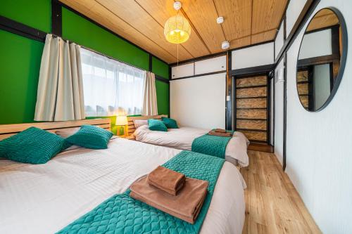 千葉市にある-Soga House-古民家の宿の緑の壁の部屋にベッドが2つある