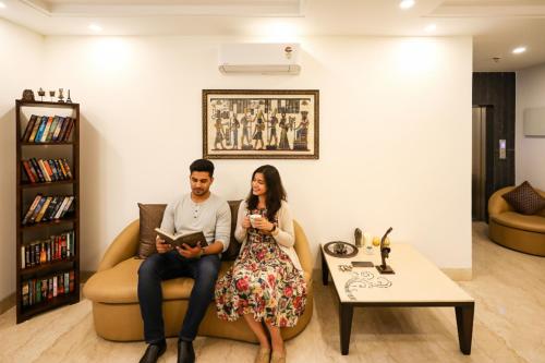un hombre y una mujer sentados en un sofá en una sala de estar en FabHotel La Paz Stay B&B, en Nueva Delhi