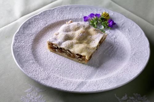 a piece of cake on a white plate with purple flowers at Albergo Scarpone in Forni Avoltri