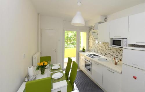 a kitchen with white cabinets and a table with green chairs at Apartmani Vedmar in Zagreb