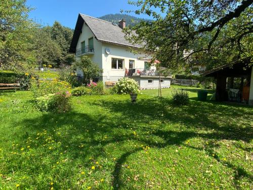 una casa con un patio con césped verde y flores en Haus Lois, en Weissbriach