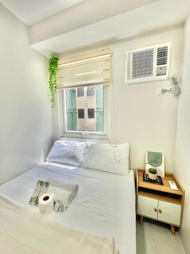a bedroom with a white bed and a window at 2BR Family Condo for 6pax near IT Park Budget Stay at Urban Deca Homes Banilad by Gerra unit Nathan in Mandaue City