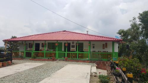 a green and white house with a red roof at Hostal y Camping Los Girasoles in Salento
