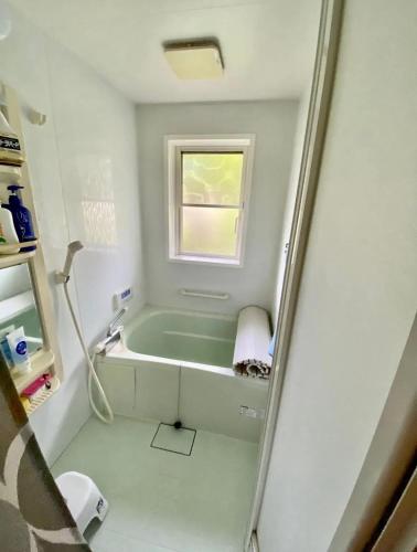 a bathroom with a bath tub and a window at コテージ杏庵 Cottage Anzuan in Minamioguni