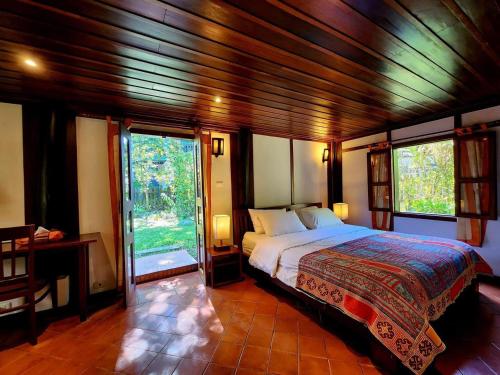 a bedroom with a bed in a room with windows at Villa Maydou Boutique Hotel in Luang Prabang