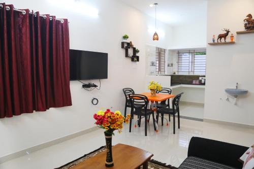 a living room with a table and a tv on the wall at Go COOL-IN in Yercaud