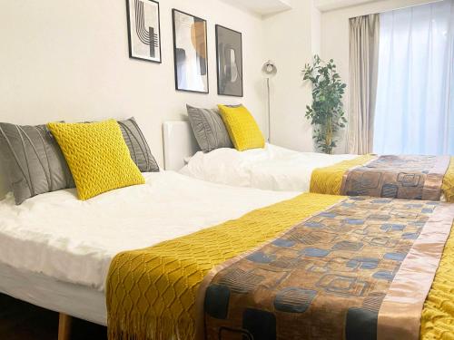 two beds in a room with yellow and white at -シーフォルム京急蒲田-Entire Unit in Tokyo