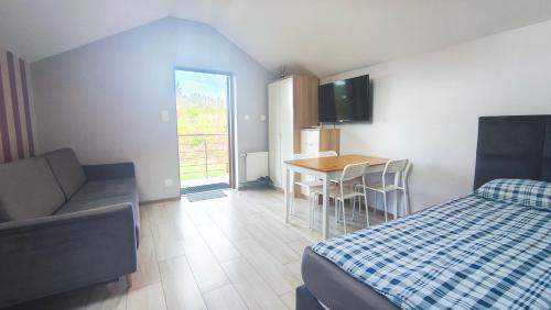 a bedroom with a bed and a table and a kitchen at Wrzosowe Wzgórze Apartamenty in Chęciny