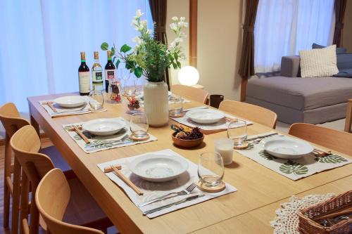 a dining room table with plates and wine glasses at KazeVillaFurano in Furano