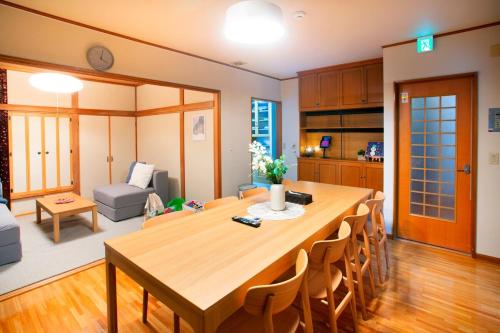a kitchen and living room with a large wooden table at KazeVillaFurano in Furano