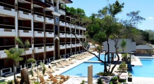 un hôtel avec une piscine, des chaises et un bâtiment dans l'établissement MO2 Westown Hotel San Juan, à Bacolod