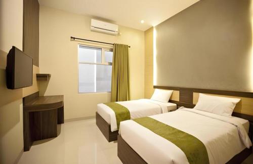 a hotel room with two beds and a television at dPalma Hotel in Bandung
