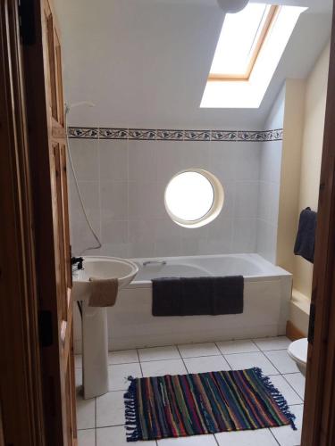 a bathroom with a tub and a sink and a window at Cois Chnoic in Dingle