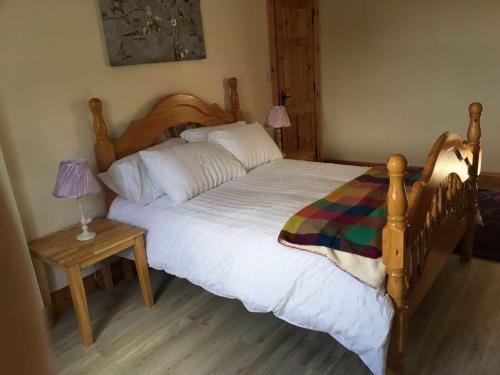 a bedroom with a large wooden bed and a table at Cois Chnoic in Dingle