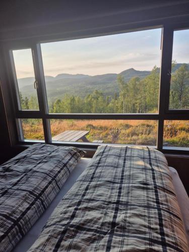 a bed in a room with a large window at Modern mountain cabin with panorama view in Eggedal