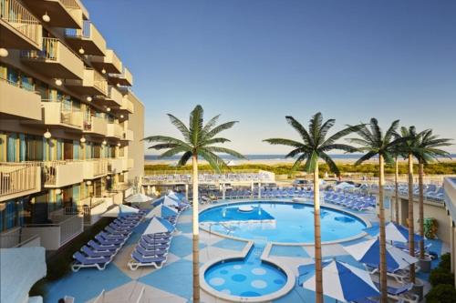 a resort with a pool and chairs and palm trees at Pan American Oceanfront Hotel in Wildwood Crest