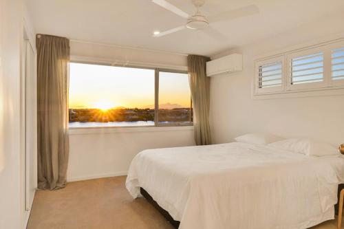 Un dormitorio con una cama y una ventana con la puesta de sol. en Waterfront-Bay View, en Port Macquarie