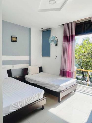 two beds sitting in a room with a window at Cát Tường Homestay in Danang