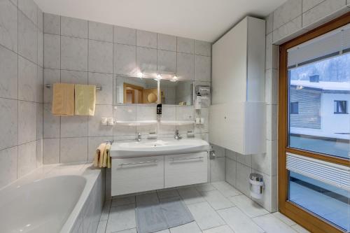 a white bathroom with a tub and a sink at Ferienwohnungen Haus Daheim in Längenfeld